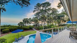 A poolside deck with a view of the ocean and a pool.