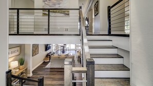 A multi-level interior with a staircase, a dining area, and artwork on the walls.