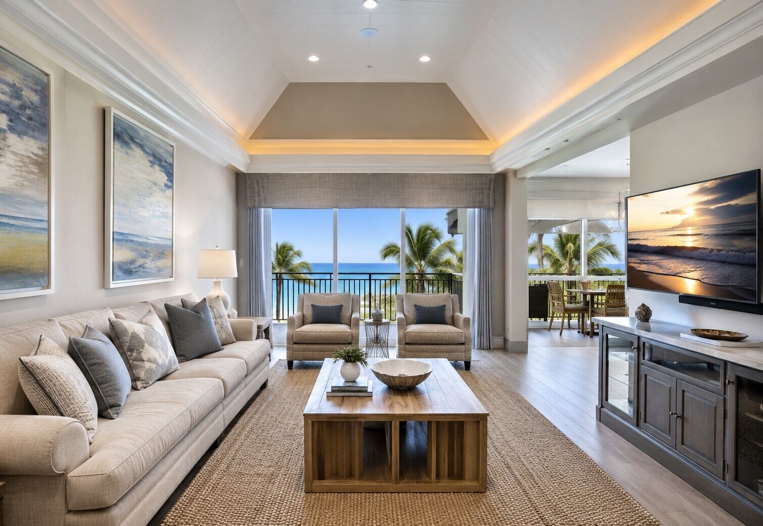 Un vaste espace de vie avec une grande fen être donnant sur un balcon d’où l’on peut admirer l’océan. On y trouve un canapé, deux fauteuils et une table basse agrémentée d’objets décoratifs.