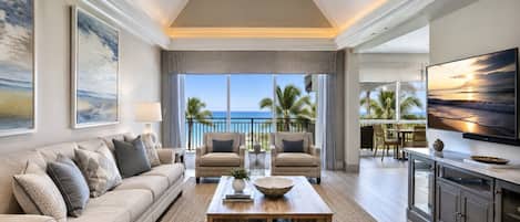 A spacious living area with a large window overlooking a balcony with a view of the ocean. There is a sofa, two armchairs, and a coffee table with decorative items.