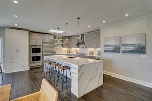 A modern kitchen with a large island, stainless steel appliances, and pendant lighting.