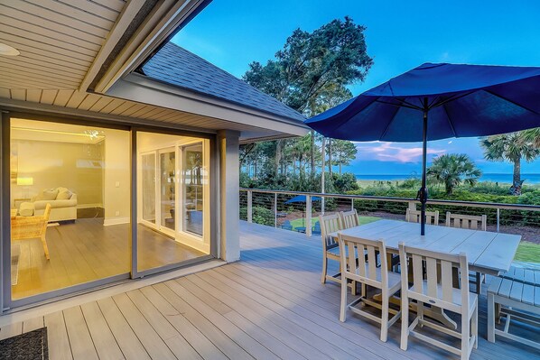 A deck with outdoor furniture and a view of the ocean.