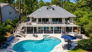 A two-story house with a swimming pool, outdoor furniture, and a covered patio area.