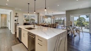 A spacious kitchen with a large island, pendant lighting, and a view to the outdoors.