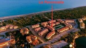 Eine Luftaufnahme von La Pavonella, einem Küstenwohngebiet mit angeordneten Häusern, einer Grünfläche im Zentrum und Nähe zum Strand.