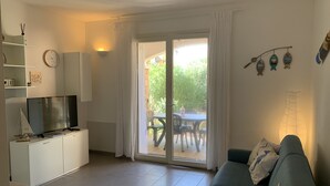 Ein modernes Wohnzimmer mit Sofa, Fernseher und einem Essbereich mit Tisch und Stühlen.