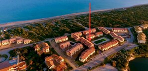 Vue aérienne de La Pavonella, un quartier résidentiel situé sur la côte, caractérisé par des logements bien aménagés, un espace vert central et sa proximité avec la plage.