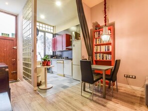 A compact kitchen with modern appliances, a dining area with a table and chairs, and a bookshelf with books. - apartamento castizo en madrid rio de alquiler temporal (Madrid)
