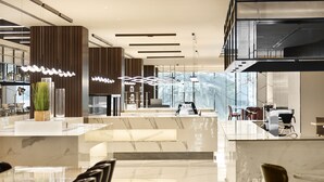 En moderne hotellobby med en receptionsdisk i marmor, høje lofter og moderne lysarmaturer.