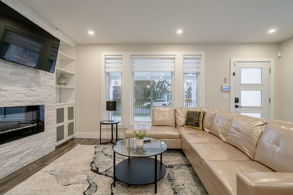 A modern living room with a fireplace, leather sofa, and a glass coffee table.