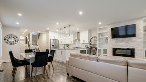 A modern kitchen with white cabinets, a built-in oven, and a flat-screen TV mounted on a stone wall. - 65 on the Main in the heart of Kingsville (Kingsville)
