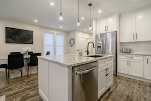 A modern kitchen with white cabinetry, stainless steel appliances, and a granite countertop. - 65 on the Main in the heart of Kingsville (Kingsville)