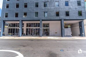 Un bâtiment moderne avec une entrée en verre, une enseigne indiquant « 227NC, 2e étage, 94 », et l’entrée d’un parking souterrain.