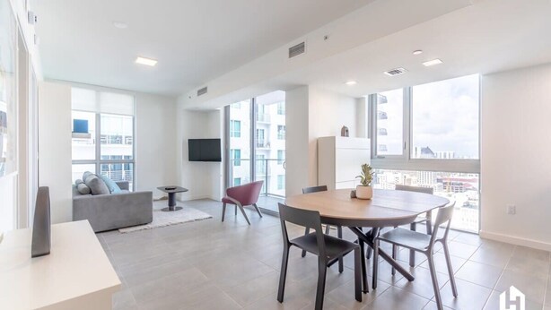 Un appartement moderne comprenant un coin repas, un salon et de grandes fenêtres offrant une vue sur la ville.
