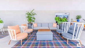 A modern lounge area with a grey sofa, white armchairs, and a colorful plaid rug. - Downtown Stay | Restaurant, Gym, Pool & CoWork! (Miami)