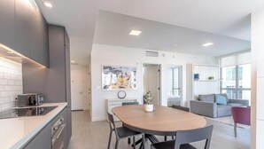A modern kitchen with a dining area, a large painting on the wall, and a view of the city through the window. - Downtown Stay | Restaurant, Gym, Pool & CoWork! (Miami)