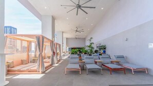 A modern indoor lounge with ceiling fans, a seating area with loungers, and a view of the cityscape. - Downtown Stay | Restaurant, Gym, Pool & CoWork! (Miami)