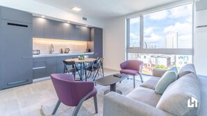 A modern apartment with a kitchen, dining area, and a living room with a large window offering a city view.