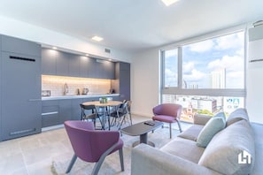 Un apartamento moderno con cocina, comedor y sala de estar con un amplio ventanal que ofrece vistas a la ciudad.