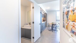 A modern kitchen with a white countertop, a sink, and a dining area with a table and chairs.