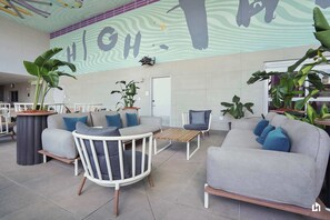 A modern lounge area with sofas, chairs, and potted plants.