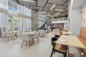 Un restaurante moderno con varias zonas de comedor, una escalera y vistas al exterior.