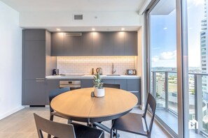 A modern kitchen with grey cabinets, a round wooden table, and a potted plant.