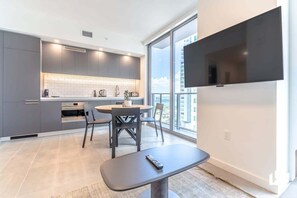 Una cocina moderna con armarios grises, salpicadero blanco de azulejos y una zona de comedor con mesa y sillas redondas.
