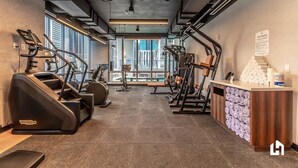 A gym with treadmills, elliptical machines, and weight equipment, with a reception desk and a view of the city. - Bayside District Studio: City Views & Pool (Miami)