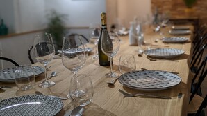 Ein Esstisch, gedeckt mit Tellern, Gläsern und Besteck, mit einer Champagnerflasche in der Mitte.