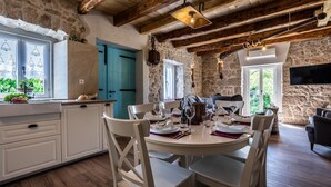 Une cuisine rustique aux murs de pierre, avec une porte bleue et un coin repas préparé pour le dîner.