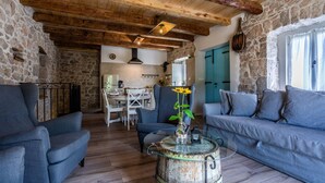 Un intérieur rustique avec des murs en pierre, des poutres en bois, un coin repas et un espace salon confortable.