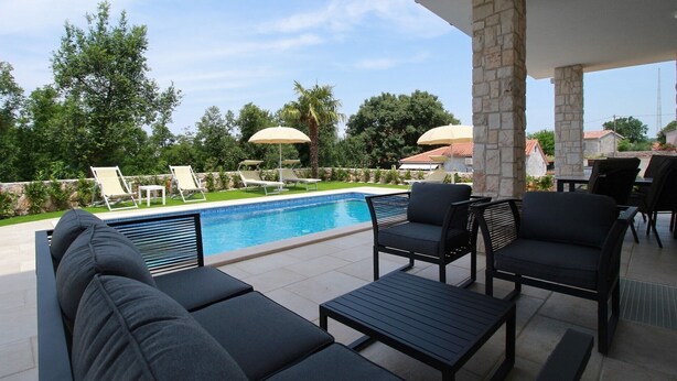 A poolside area with lounge chairs, a table, and umbrellas.