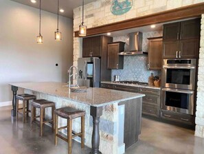 Enjoy cooking in this well-equipped kitchen with a central island, refrigerator, oven, and microwave.