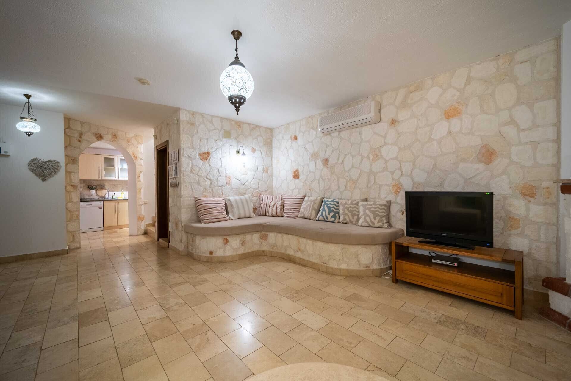 A living room with a stone wall, a curved sofa, a TV, and a wooden entertainment unit.