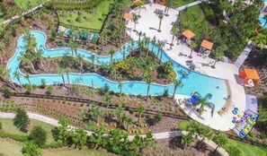 Vista aérea de um resort com piscina serpenteante, palmeiras e espreguiçadeiras.