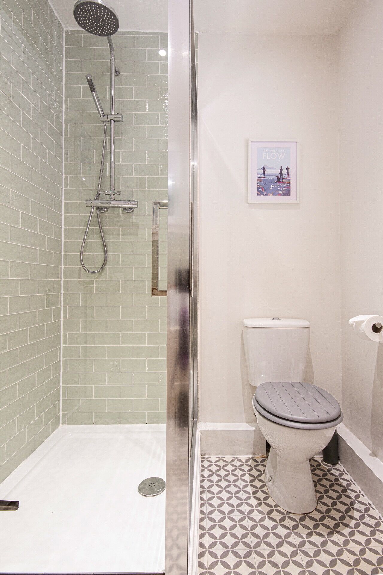 A bathroom with a shower, toilet, and a framed picture on the wall.