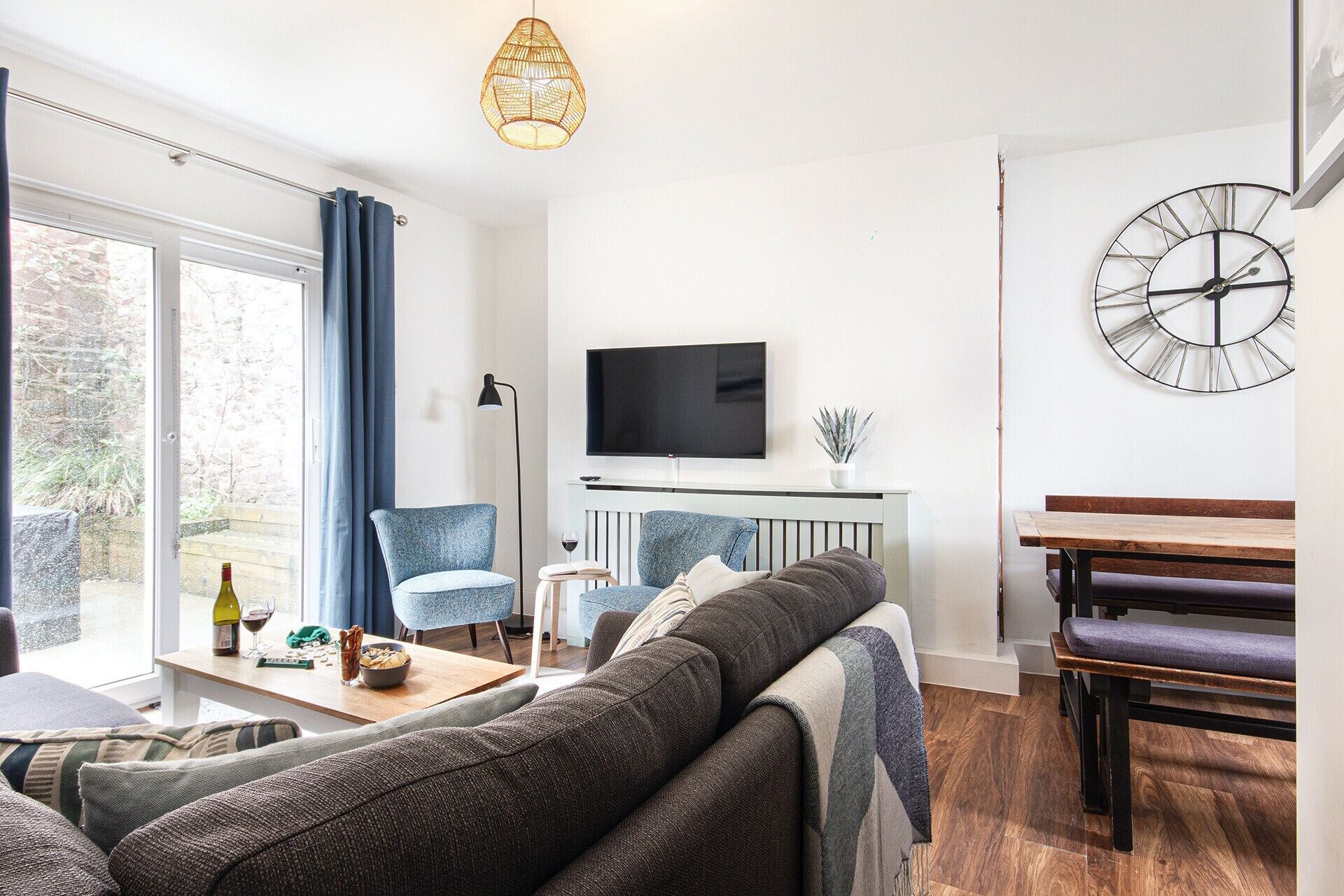Un salon moderne comprenant un canapé, une table basse, un téléviseur et un coin repas avec une banquette.