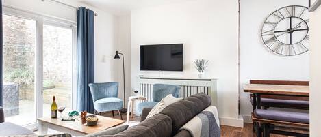 Un salon moderne comprenant un canapé, une table basse, un téléviseur et un coin repas avec une banquette.