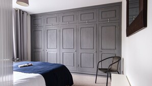 A bedroom with a bed, a chair, a wardrobe, and a mirror.