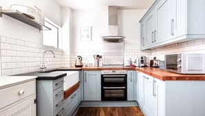 A compact kitchen with a built-in oven, a microwave, and a kettle on the countertop.