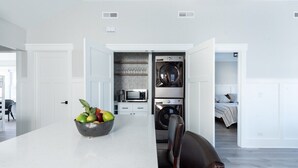 Une cuisine moderne dotée d’un îlot central, d’un lave-linge encastré et d’un four à micro-ondes.