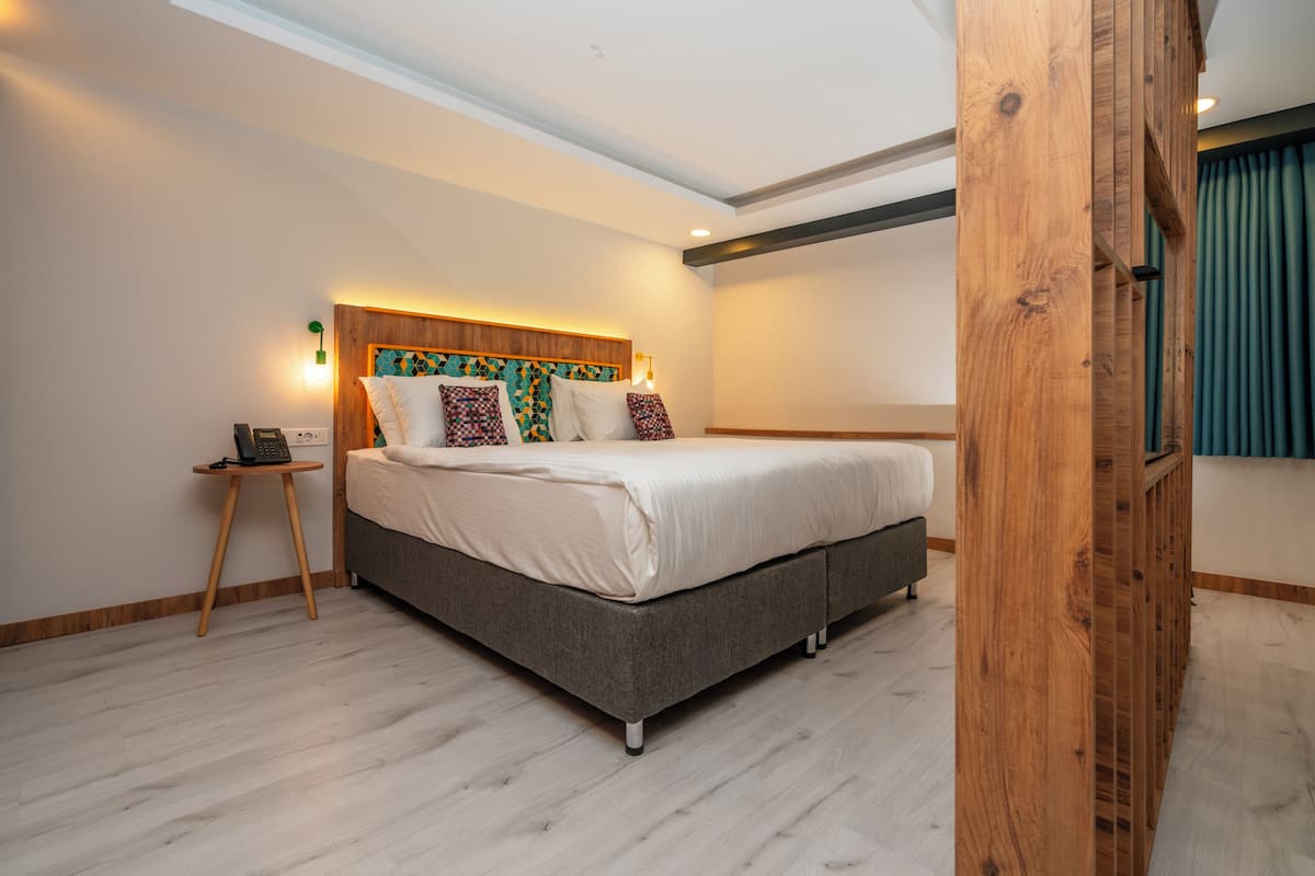 Un dormitorio moderno con una cama grande, una mesita de noche y una lámpara fijada a la pared.