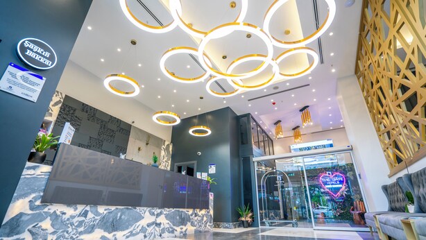 A hotel reception area with a marble reception desk, a neon sign for 'The Gate Hotels', and a modern ceiling design with circular light fixtures. - The Gate Hotels Kadıköy Downtown (Istanbul)