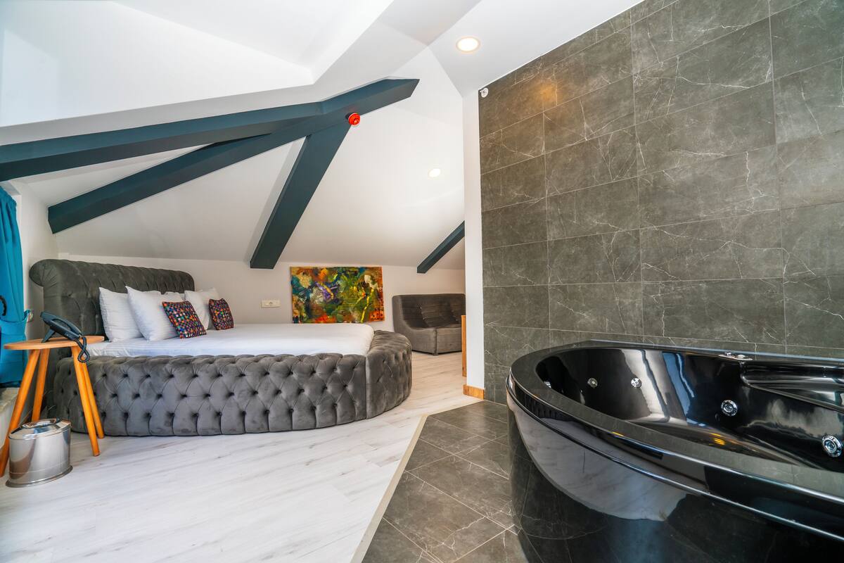 Un dormitorio moderno con una cama grande, un jacuzzi negro y un cuadro en la pared.