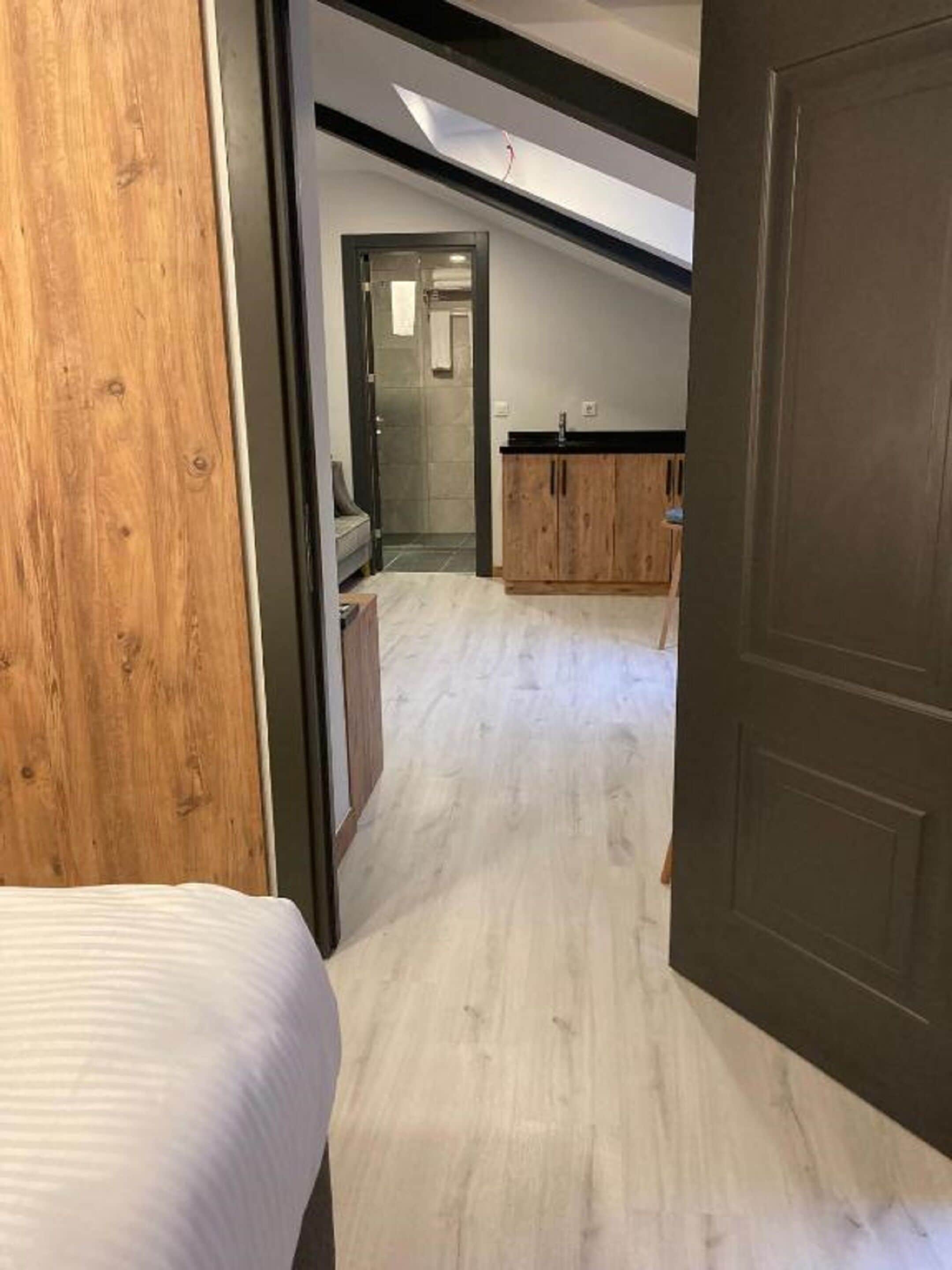 Un couloir menant à une salle de bain équipée d’une douche et d’un lavabo.
