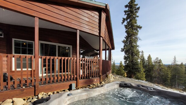 Une cabane en bois avec un jacuzzi et une terrasse.