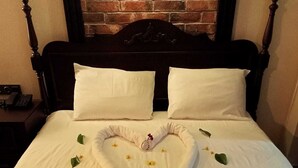 A bed with white linens, a heart-shaped towel arrangement, and scattered leaves. - Begonvil Pansiyon Konaklama (Izmir)