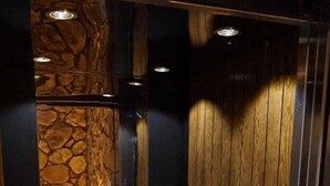 An elevator interior with a stone wall, wooden paneling, and a metal handrail. - Begonvil Pansiyon Konaklama (Izmir)