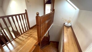 A wooden staircase with a handrail, leading to a landing with a white vase of dried flowers. - Beautiful Rural 3BR Cottage with Stunning Views - Pass the Keys (Dumfries)